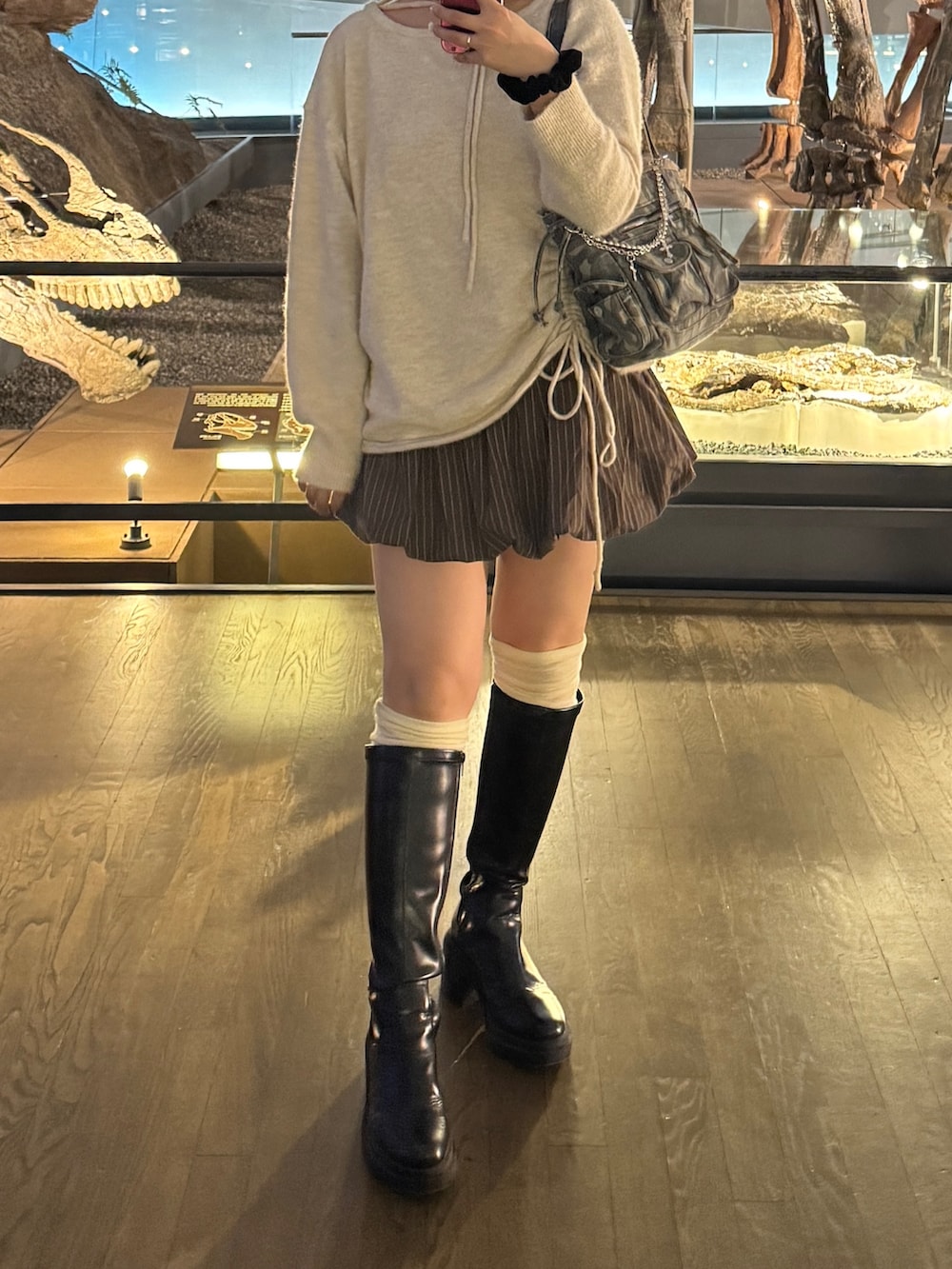 ブラウン系のスカート、ブラック系のブーツ、ベージュ系のニット/セーターを着用したレディースの冬コーディネートの2枚目の写真