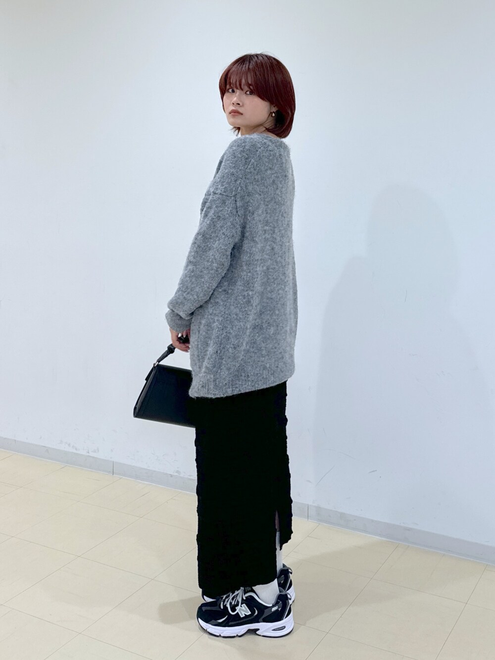 グレー系のカーディガン/ボレロ、ブラック系のスカート、ブラック系のショルダーバッグを着用したレディースの秋コーディネートの4枚目の写真