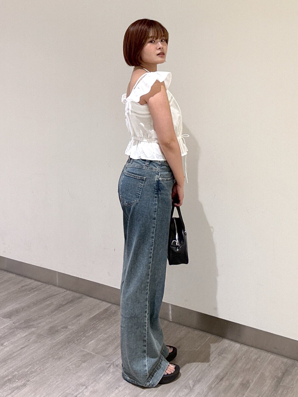 ブルー系のデニムパンツ、ブラック系のトートバッグ、ホワイト系のシャツ/ブラウスを着用したレディースの夏コーディネートの6枚目の写真