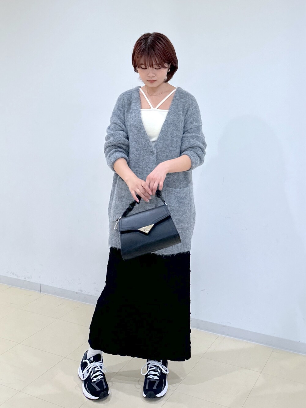 グレー系のカーディガン/ボレロ、ブラック系のスカート、ブラック系のショルダーバッグを着用したレディースの秋コーディネートの5枚目の写真