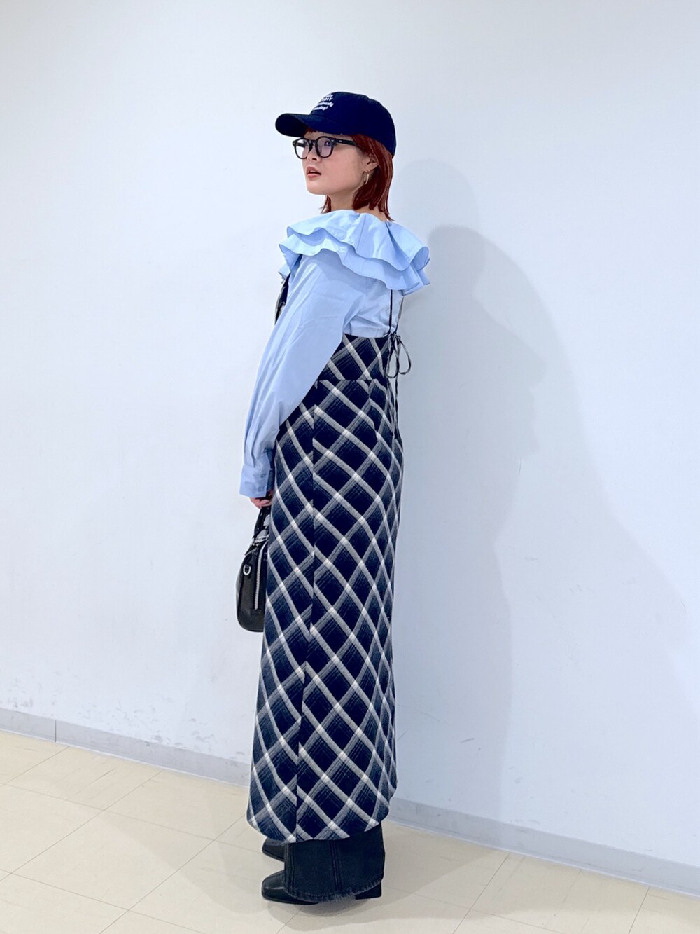 ブルー系のワンピース、ブラック系のショルダーバッグ、ブラック系のデニムパンツを着用したレディースの冬コーディネートの2枚目の写真