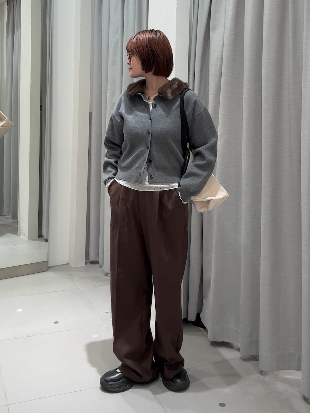 ブラウン系のスラックス、グレー系のカーディガン/ボレロ、ホワイト系のTシャツ/カットソーを着用したレディースの秋コーディネートの2枚目の写真