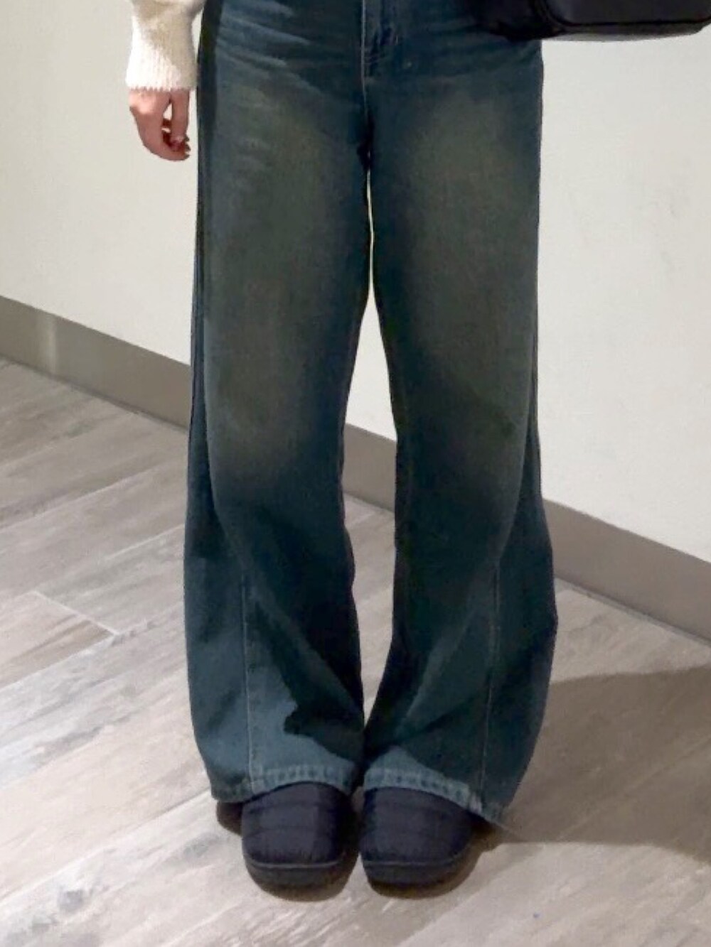 ブルー系のデニムパンツ、ブラック系のハンドバッグ、ベージュ系のニット/セーターを着用したレディースの冬コーディネートの6枚目の写真