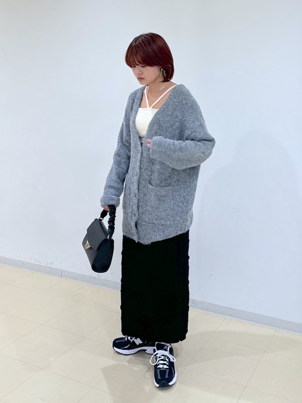 グレー系のカーディガン/ボレロ、ブラック系のスカート、ブラック系のショルダーバッグを着用したレディースの秋コーディネートの2枚目の写真