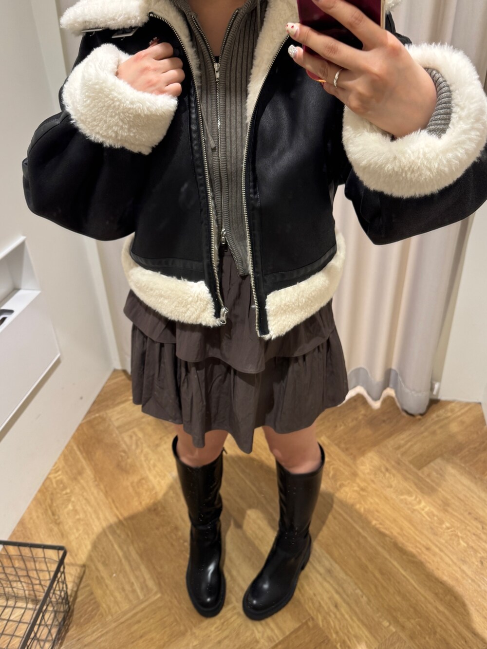 ブラック系のブルゾン、ブラック系のブーツ、ブラウン系のスカートを着用したレディースの冬コーディネートの3枚目の写真
