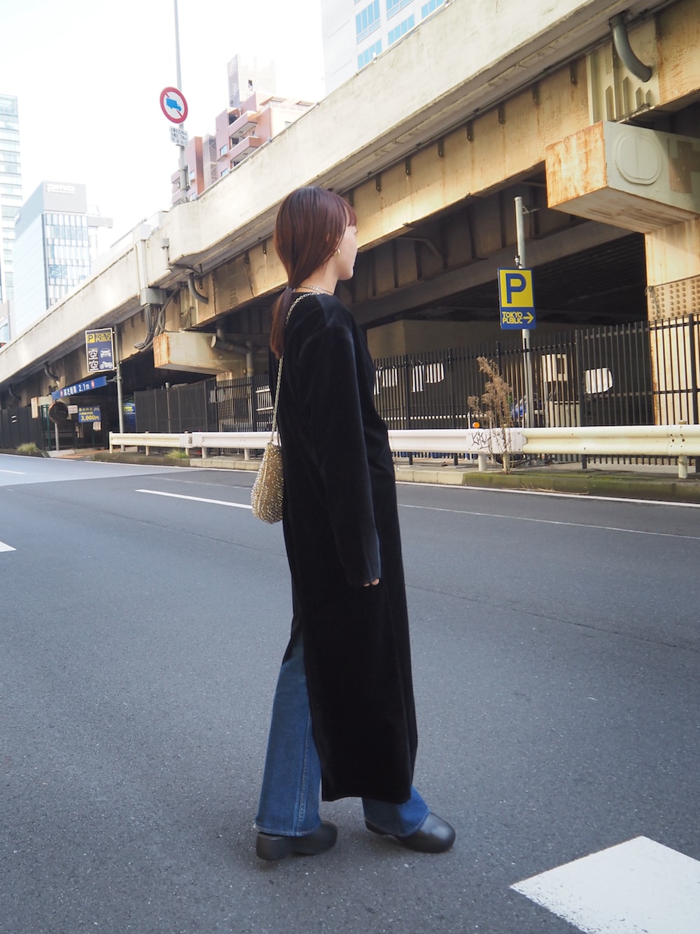 ブラック系のワンピース、ベージュ系のバッグ、ブルー系のデニムパンツを着用したレディースの秋コーディネートの3枚目の写真