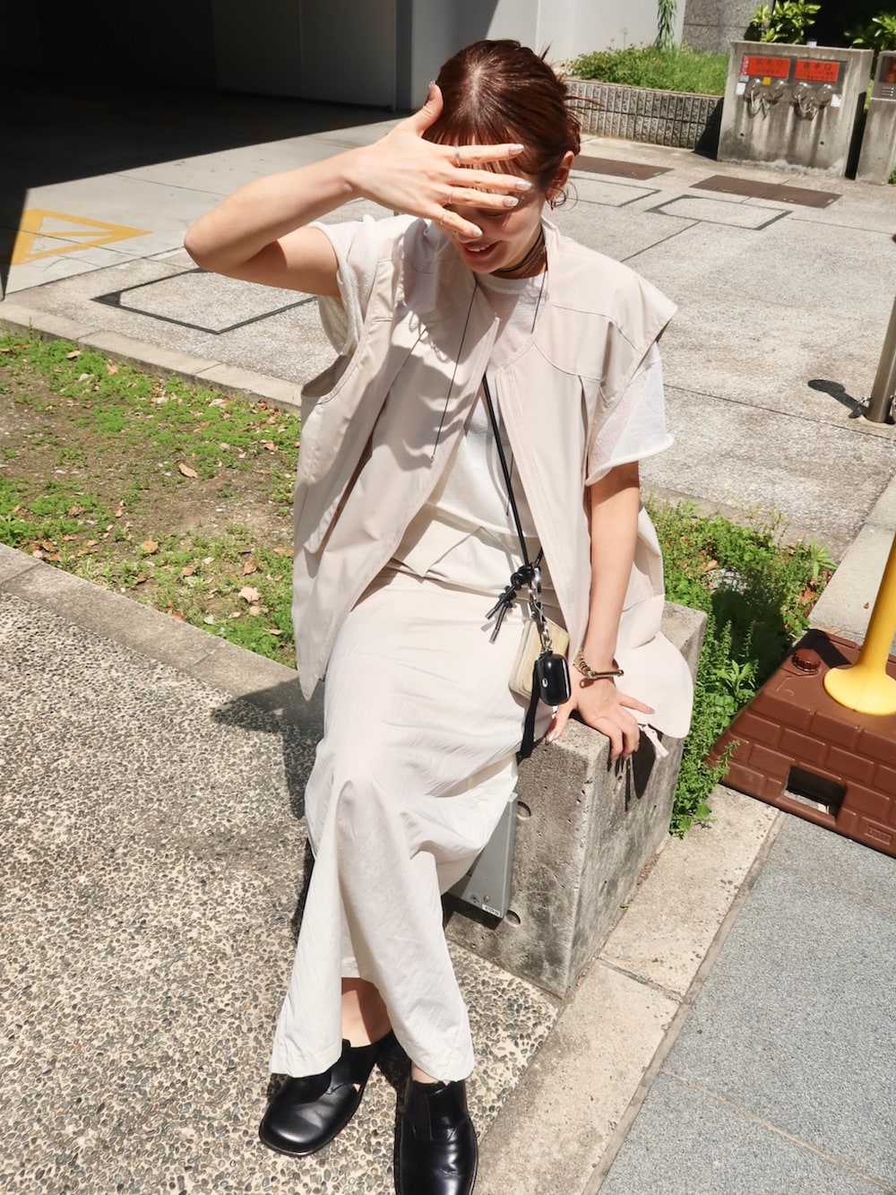 ホワイト系のニット/セーター、ベージュ系のベスト、ブラック系のスリッポンを着用したレディースの春コーディネートの2枚目の写真