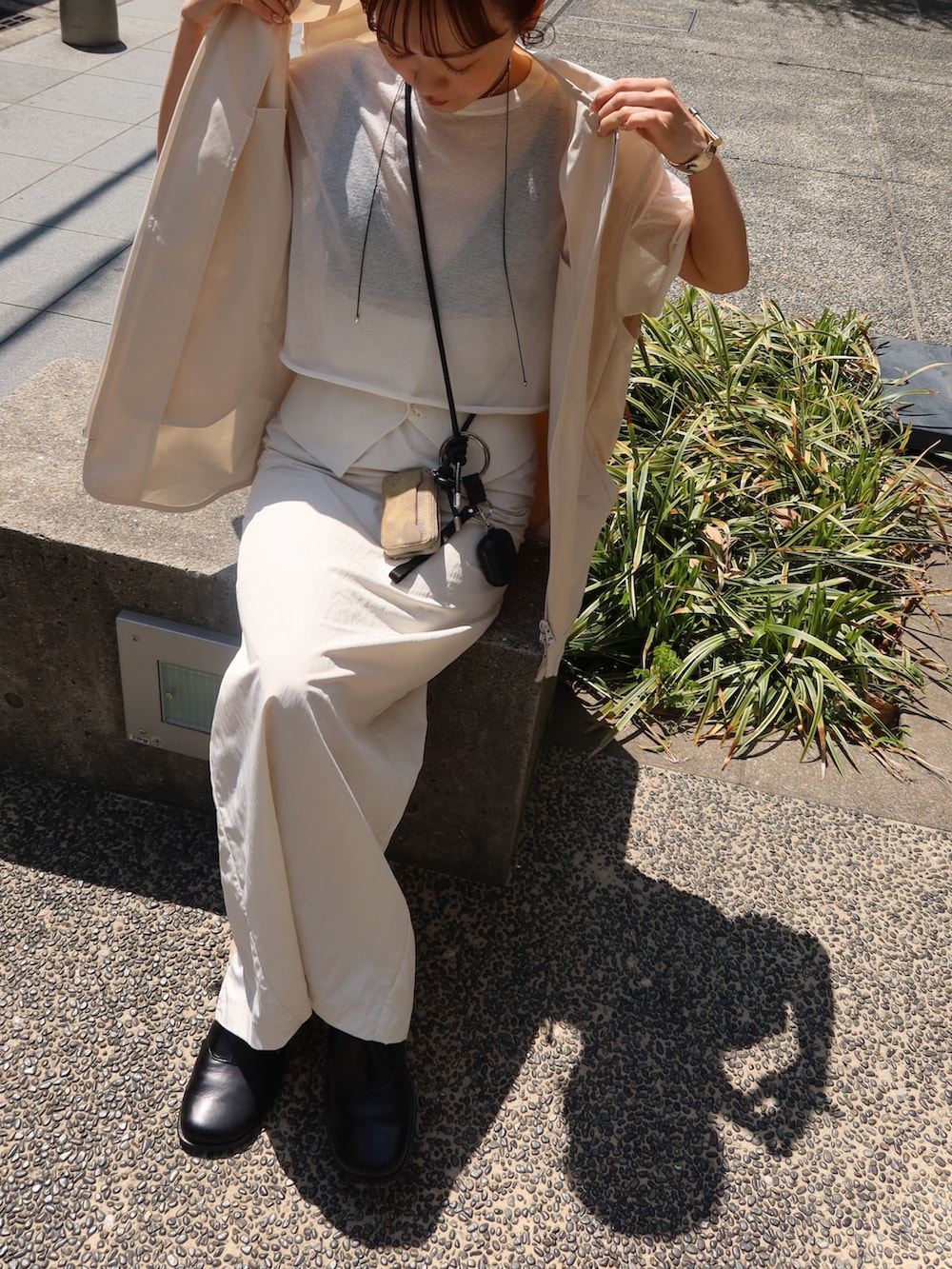 ホワイト系のニット/セーター、ベージュ系のベスト、ブラック系のスリッポンを着用したレディースの春コーディネートの3枚目の写真