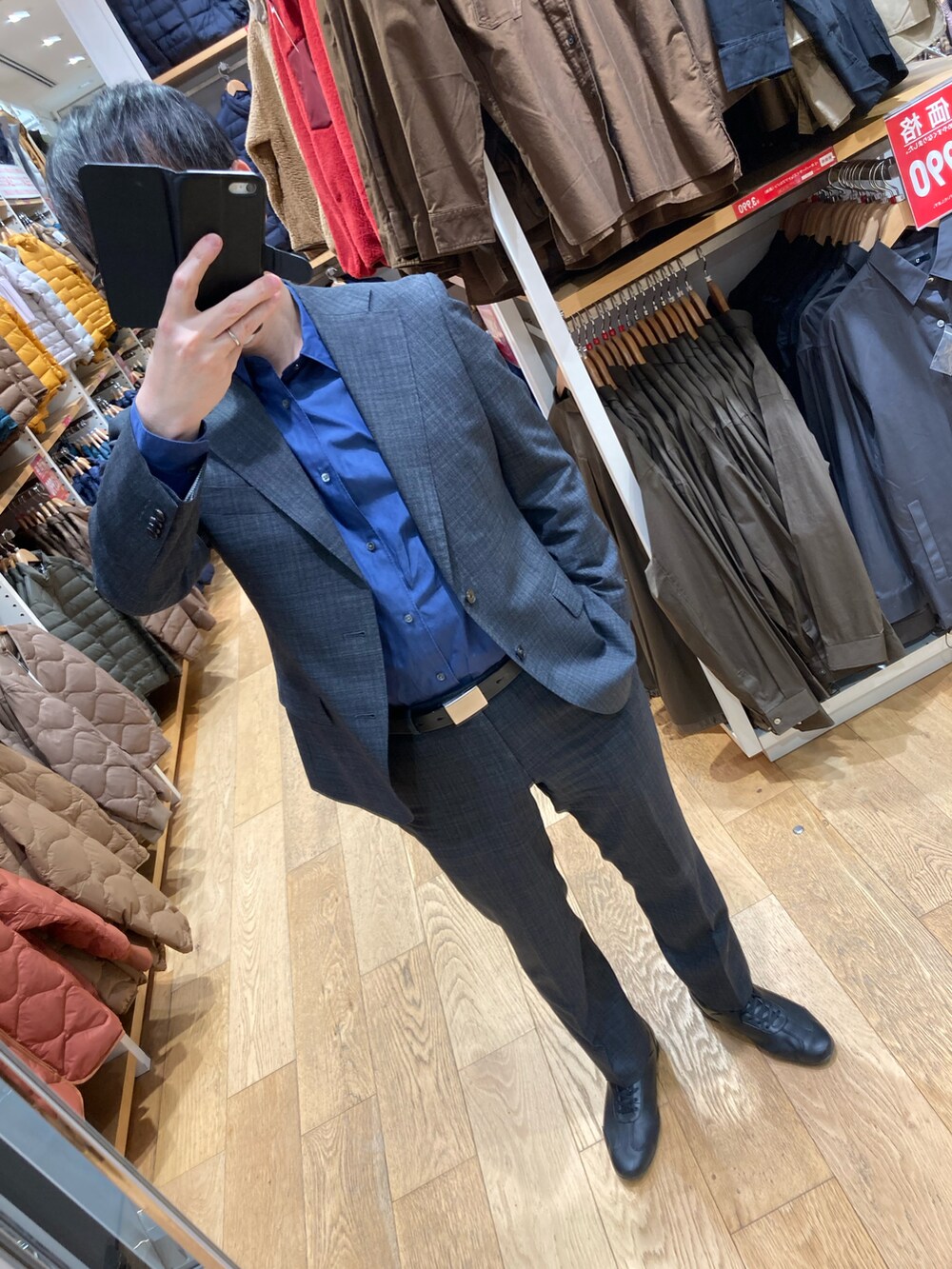 ブラック系のチェスターコート、ブラック系のスニーカー、ブルー系のビジネスシャツを着用したメンズの冬コーディネートの2枚目の写真