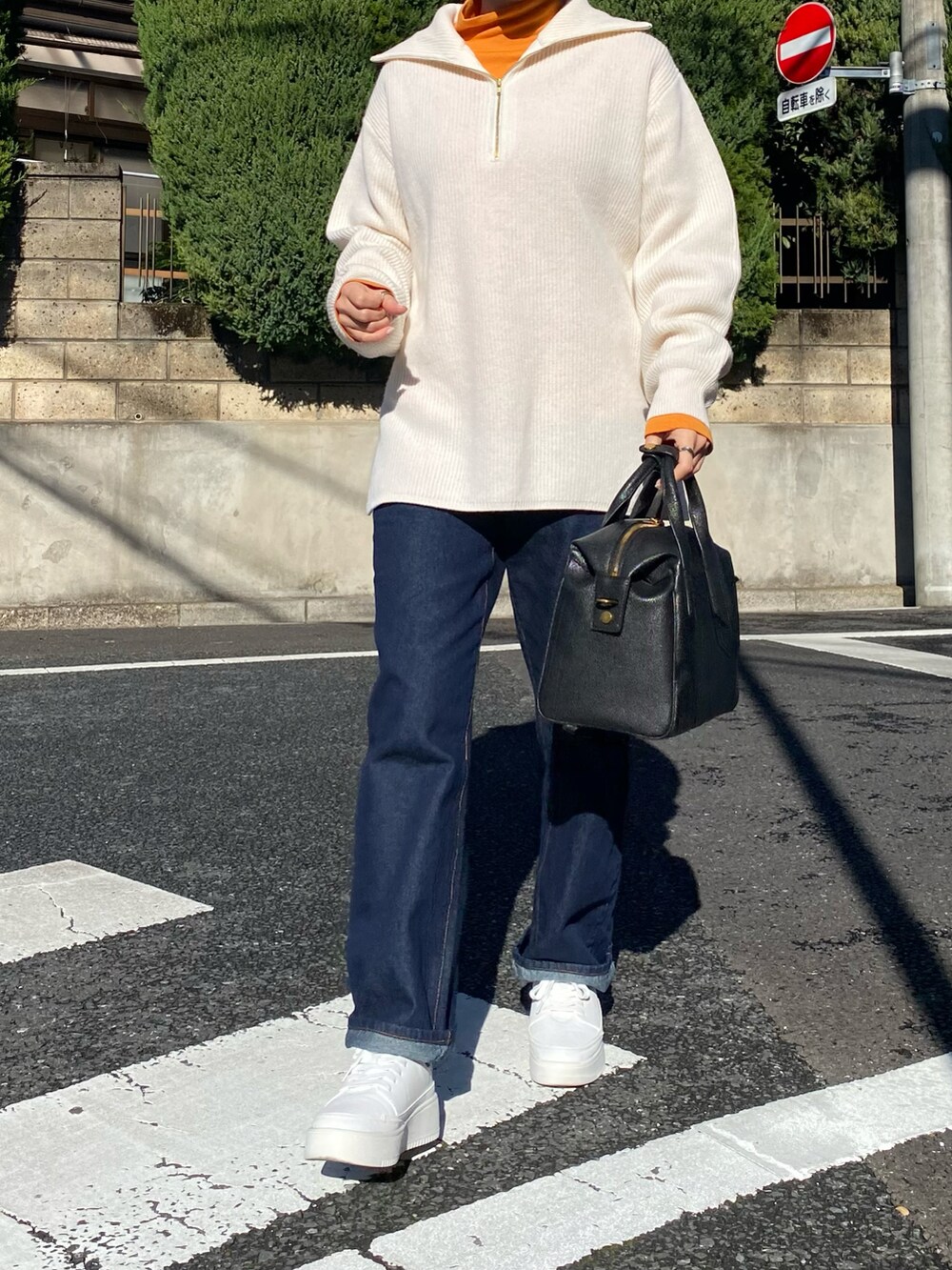 ホワイト系のニット/セーター、ブラック系のボストンバッグ、オレンジ系のTシャツ/カットソーを着用したレディースの冬コーディネートの2枚目の写真