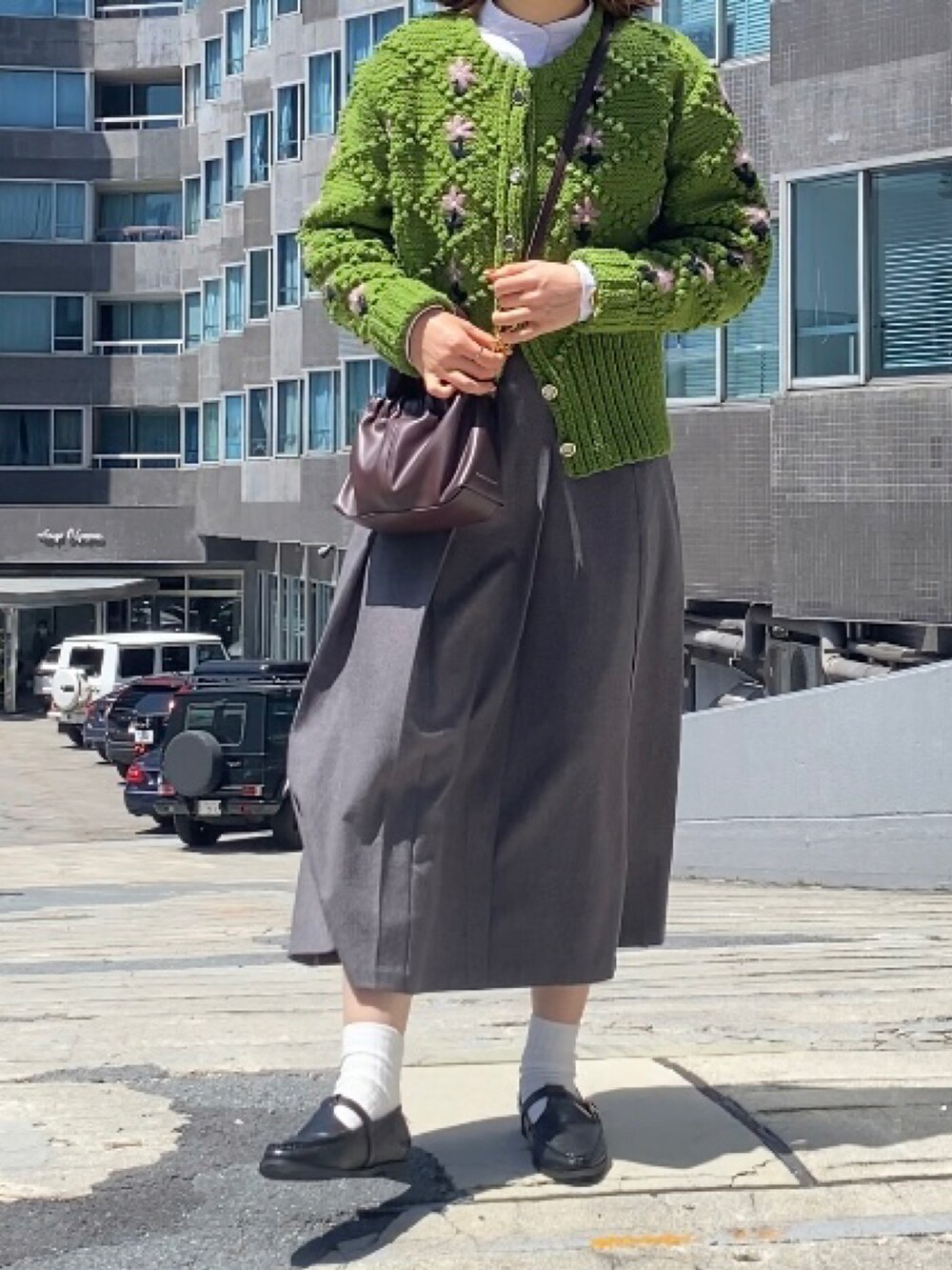 グレー系のスカート、ブラック系のローファー、ブラウン系のバッグを着用したレディースの春コーディネートの2枚目の写真