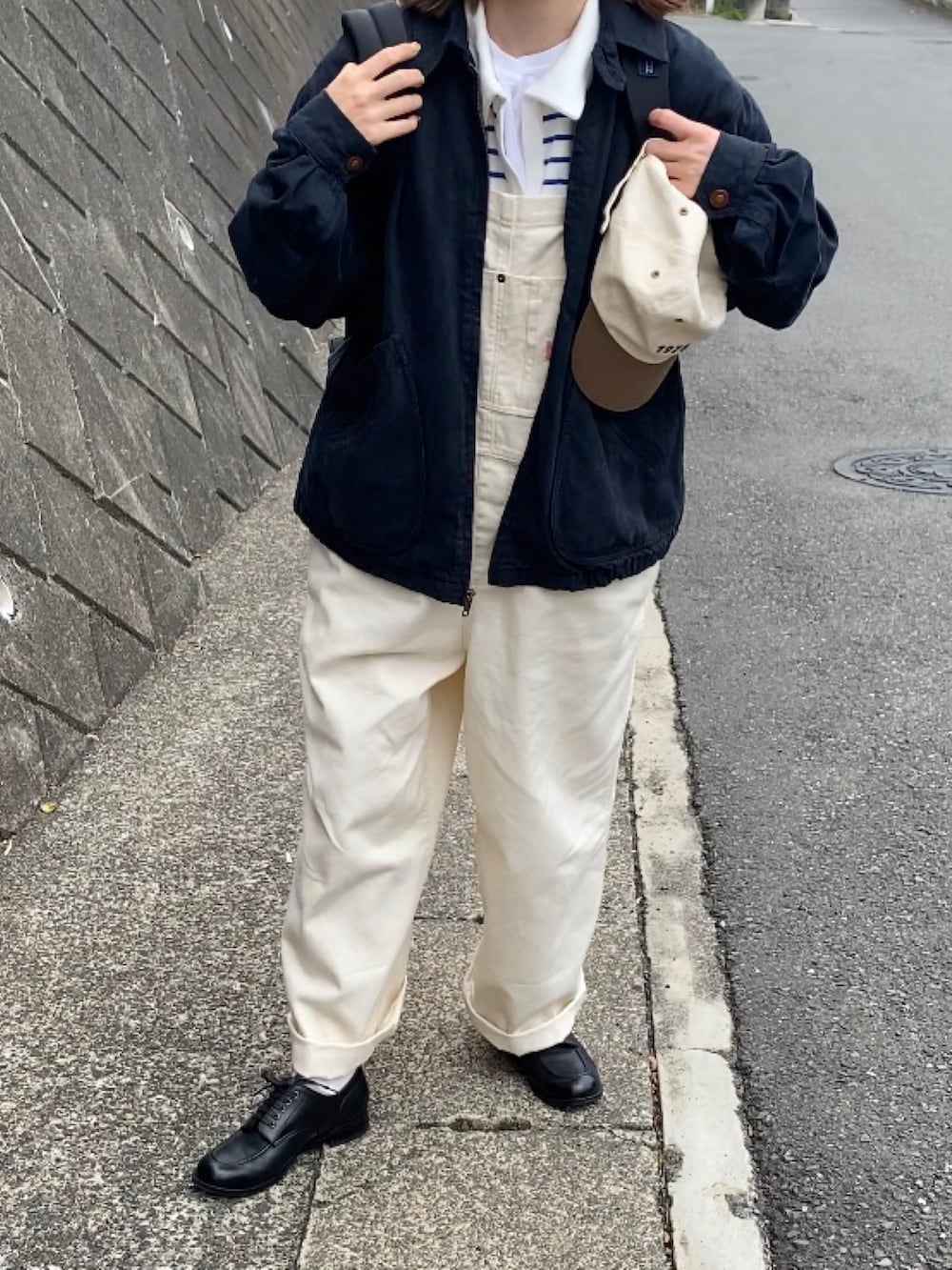 ホワイト系のサロペット/オーバーオール、ブルー系のTシャツ/カットソー、ブラック系のドレスシューズを着用したレディースの春コーディネートの2枚目の写真