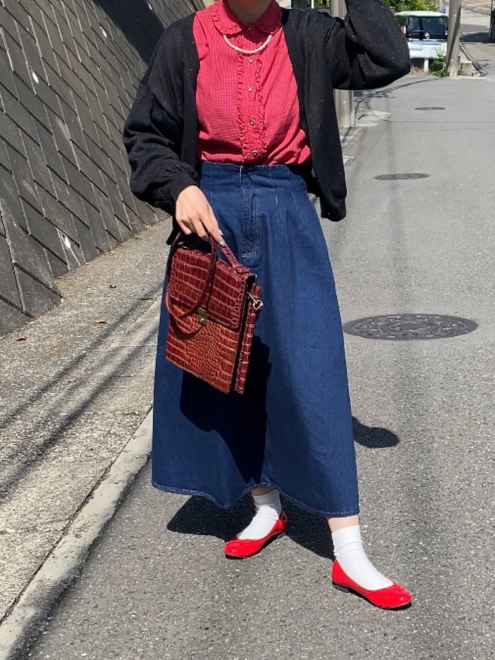 レッド系のバレエシューズ、ブルー系のデニムスカート、ブラウン系のショルダーバッグを着用したレディースの春コーディネートの2枚目の写真