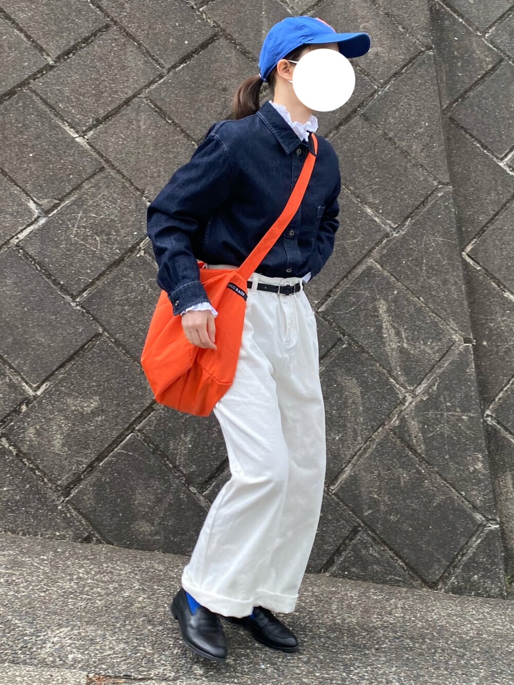 ブルー系のデニムジャケット、オレンジ系のショルダーバッグ、ブルー系のキャップを着用したレディースの春コーディネートの3枚目の写真