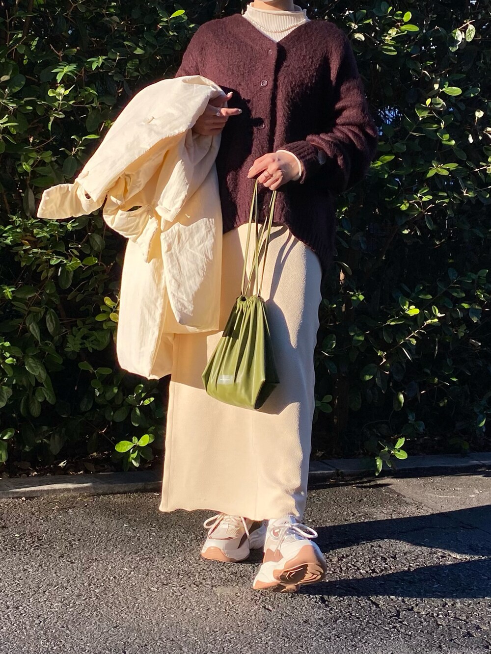 ホワイト系のダウンジャケット/コート、ブラウン系のカーディガン/ボレロ、グリーン系のショルダーバッグを着用したレディースの冬コーディネートの2枚目の写真