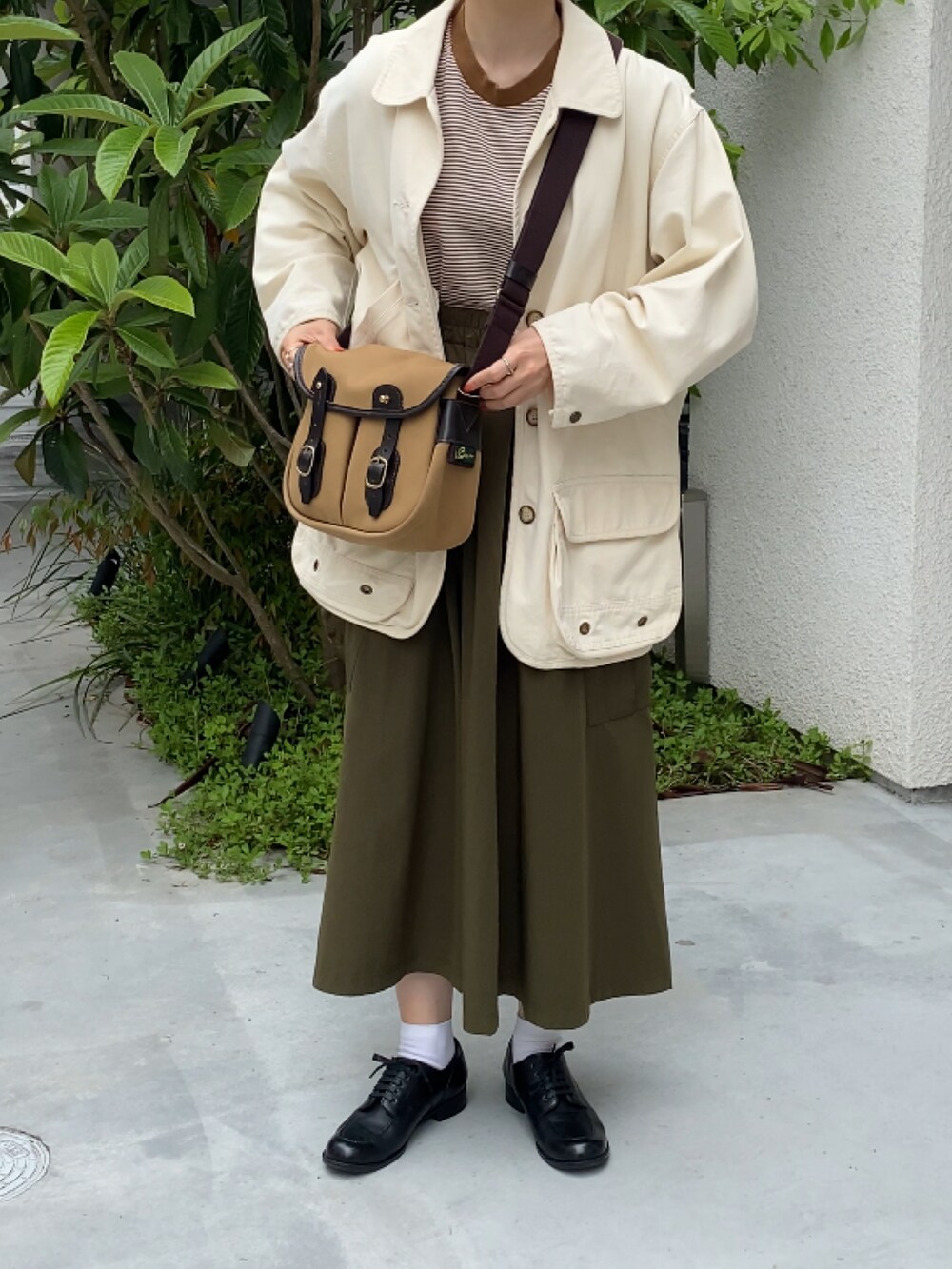 ブラウン系のショルダーバッグ、ブラック系のドレスシューズ、ホワイト系のジャケット/アウターを着用したレディースの春コーディネートの2枚目の写真