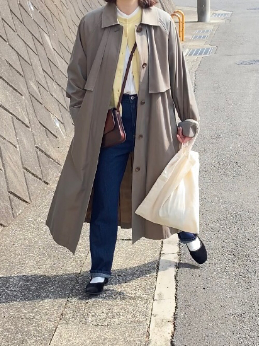 ブラウン系のショルダーバッグ、ブラック系のバレエシューズ、ブルー系のデニムパンツを着用したレディースの春コーディネートの3枚目の写真