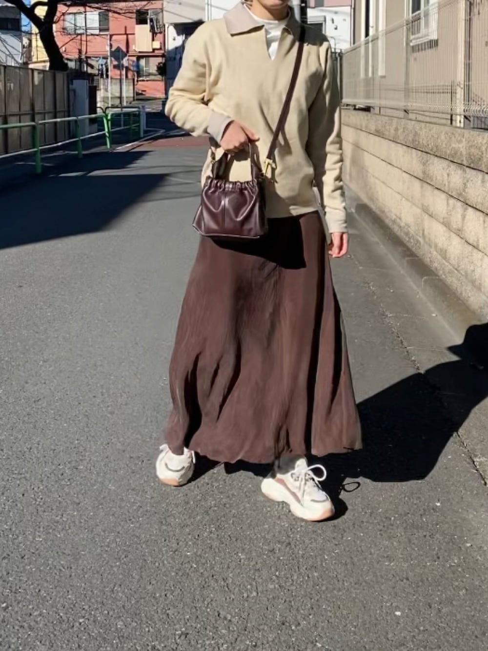 ブラウン系のダウンジャケット/コート、ブラウン系のバッグ、ブラウン系のスカートを着用したレディースの冬コーディネートの3枚目の写真