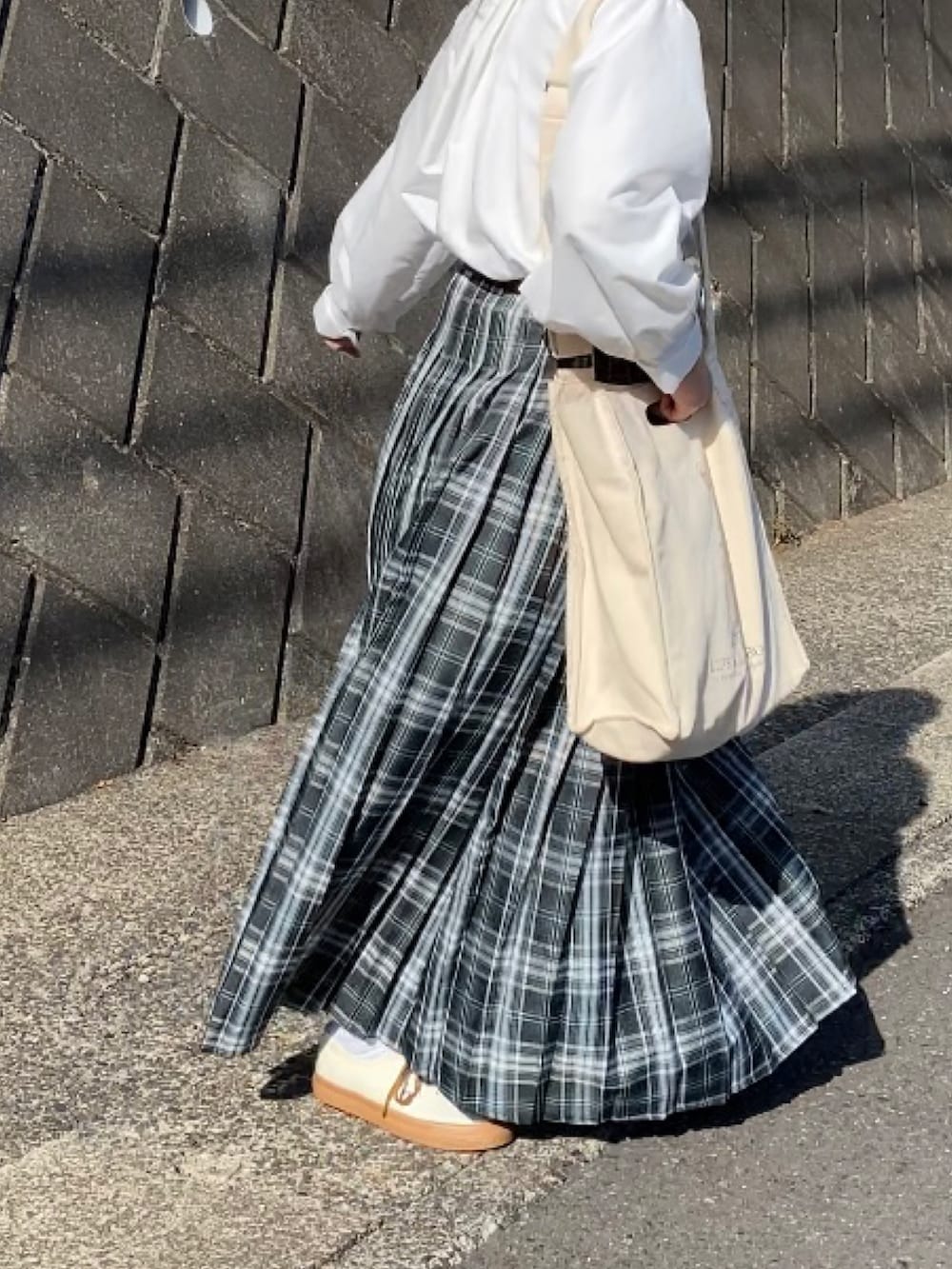 ベージュ系のスニーカー、ブルー系のスカート、ホワイト系のシャツ/ブラウスを着用したレディースの春コーディネートの4枚目の写真