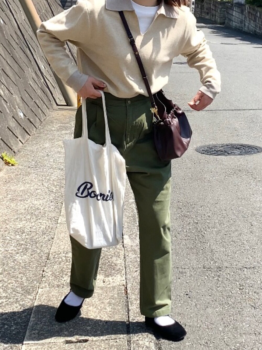 ブラック系のバレエシューズ、グリーン系のパンツ、ブラウン系のバッグを着用したレディースの春コーディネートの2枚目の写真