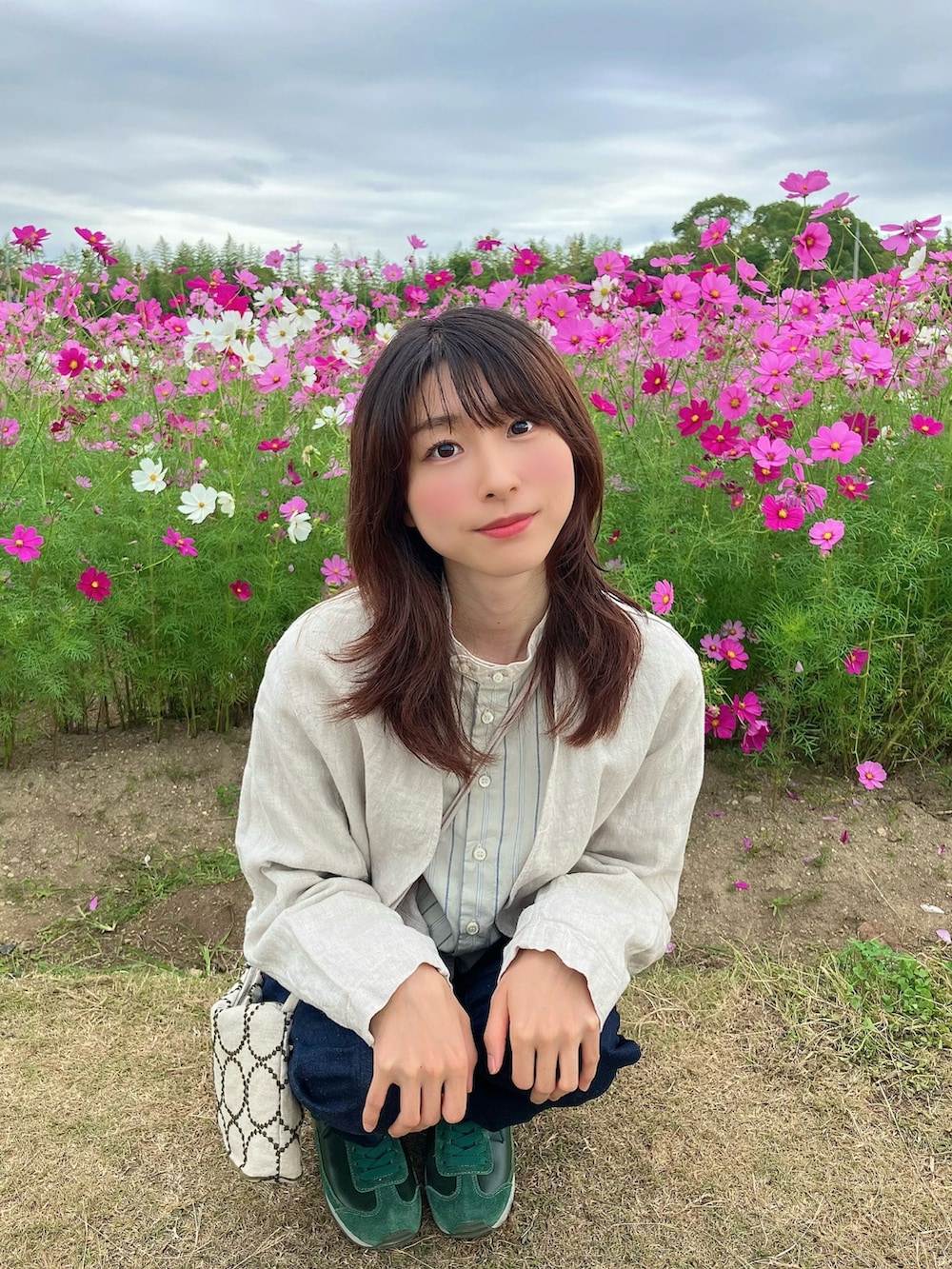 ベージュ系のショルダーバッグ、ブルー系のデニムパンツ、ベージュ系のノーカラージャケットを着用したレディースの秋コーディネートの2枚目の写真