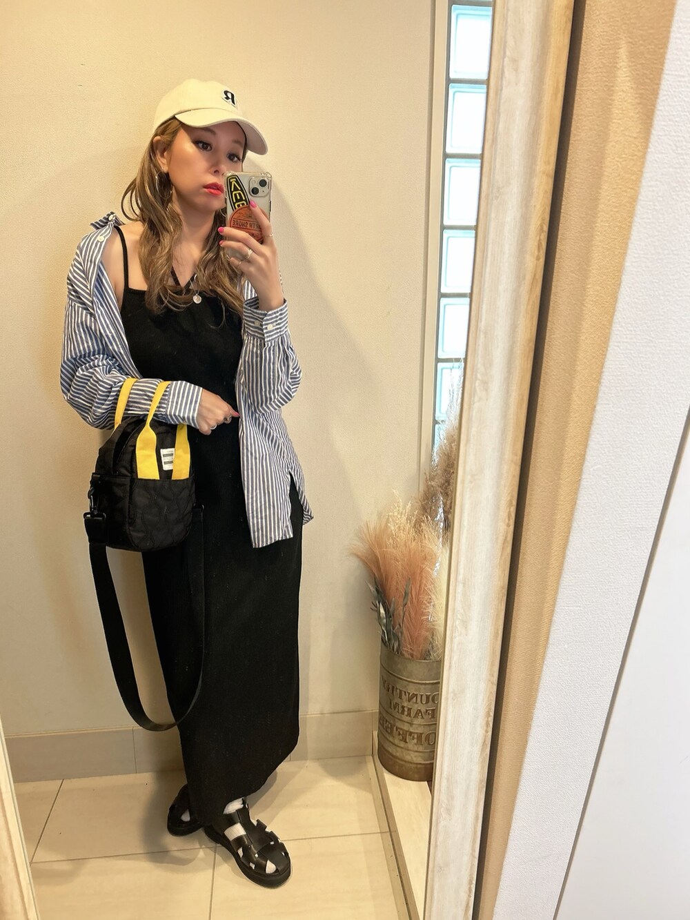 ブラック系のワンピース、ブラック系のトートバッグ、ブルー系のシャツ/ブラウスを着用したレディースの春コーディネートの2枚目の写真