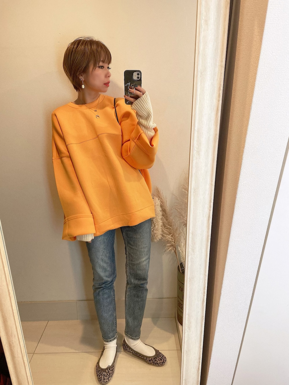 オレンジ系のスウェット、その他のバレエシューズ、ホワイト系のショルダーバッグを着用したレディースの冬コーディネートの3枚目の写真