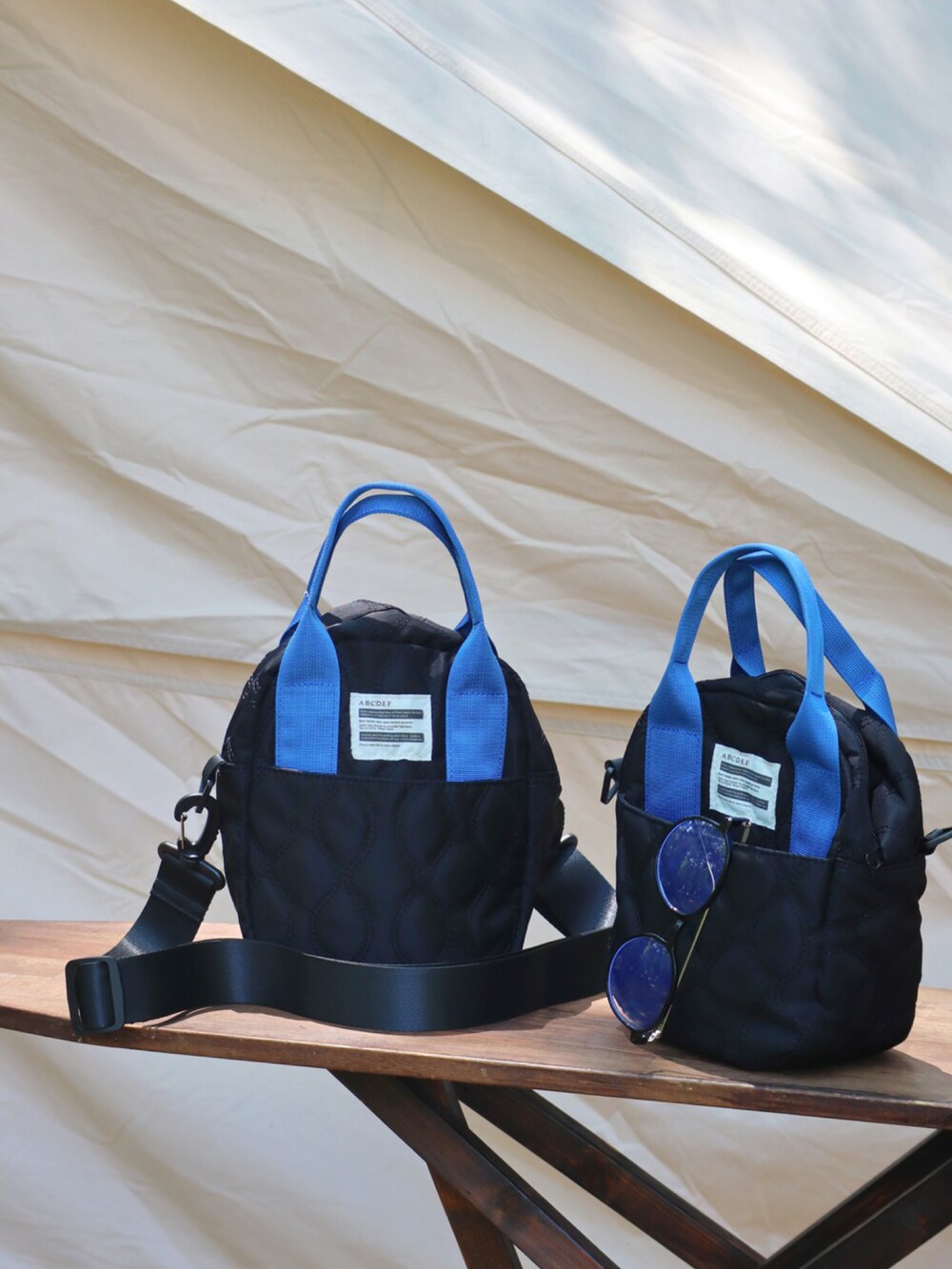 ブラック系のトートバッグ、ブラック系のサンダル、ベージュ系のハットを着用したレディースの夏コーディネートの3枚目の写真