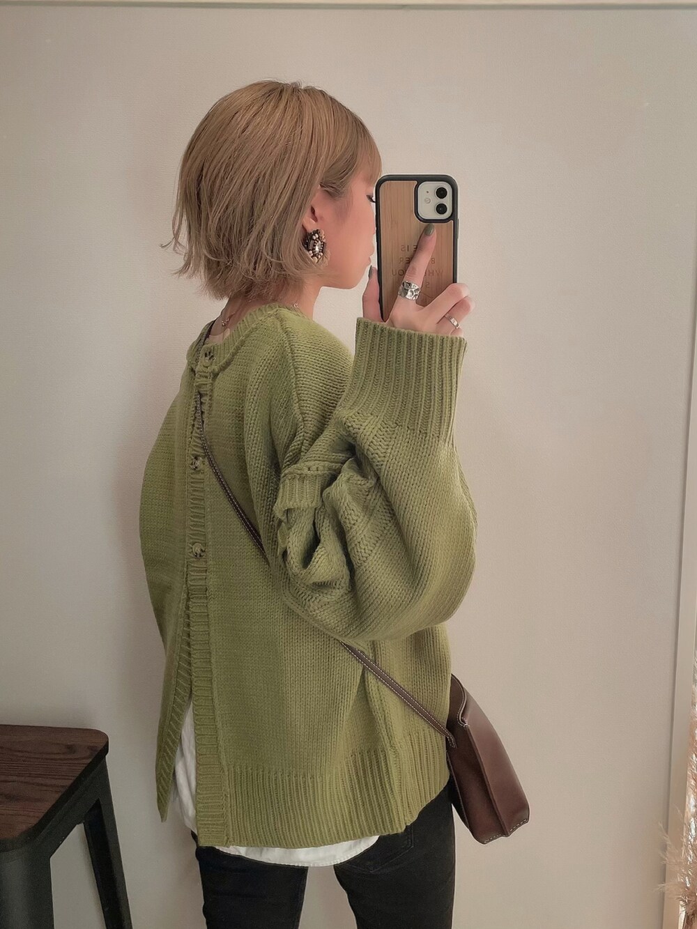 グリーン系のニット/セーター、ブラック系のブーツ、ブラック系のデニムパンツを着用したレディースの冬コーディネートの4枚目の写真