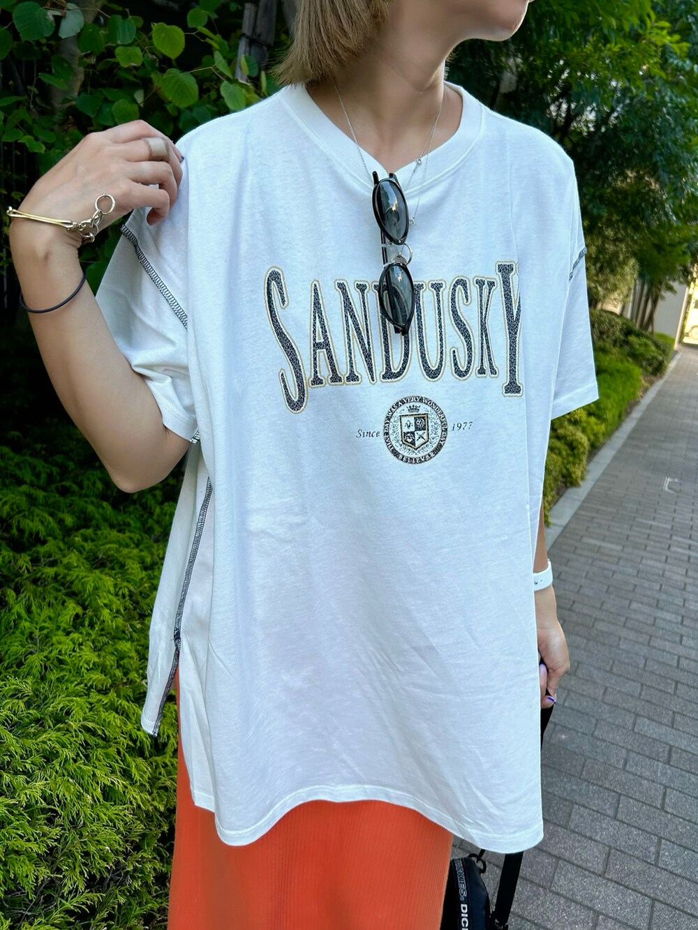 ホワイト系のTシャツ/カットソー、オレンジ系のスカート、ブラック系のサンダルを着用したレディースの夏コーディネートの3枚目の写真