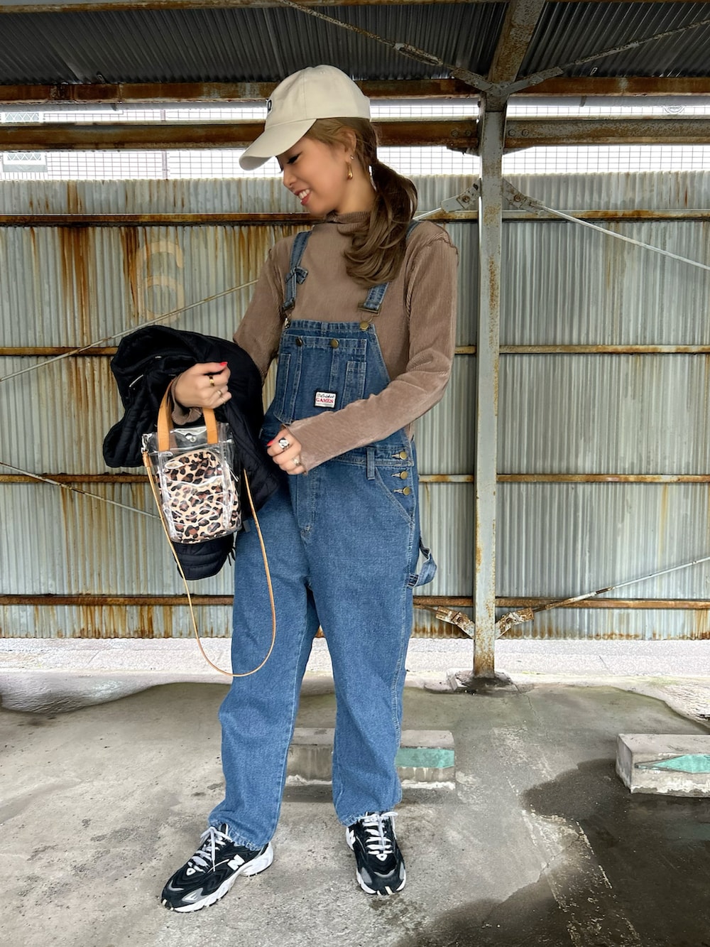 ブラウン系のTシャツ/カットソー、ブラック系のスニーカー、ベージュ系のショルダーバッグを着用したレディースの春コーディネートの3枚目の写真