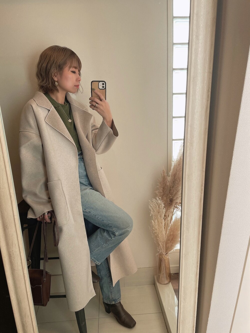 ブラウン系のチェスターコート、ブラウン系のブーツを着用したレディースの秋コーディネートの2枚目の写真