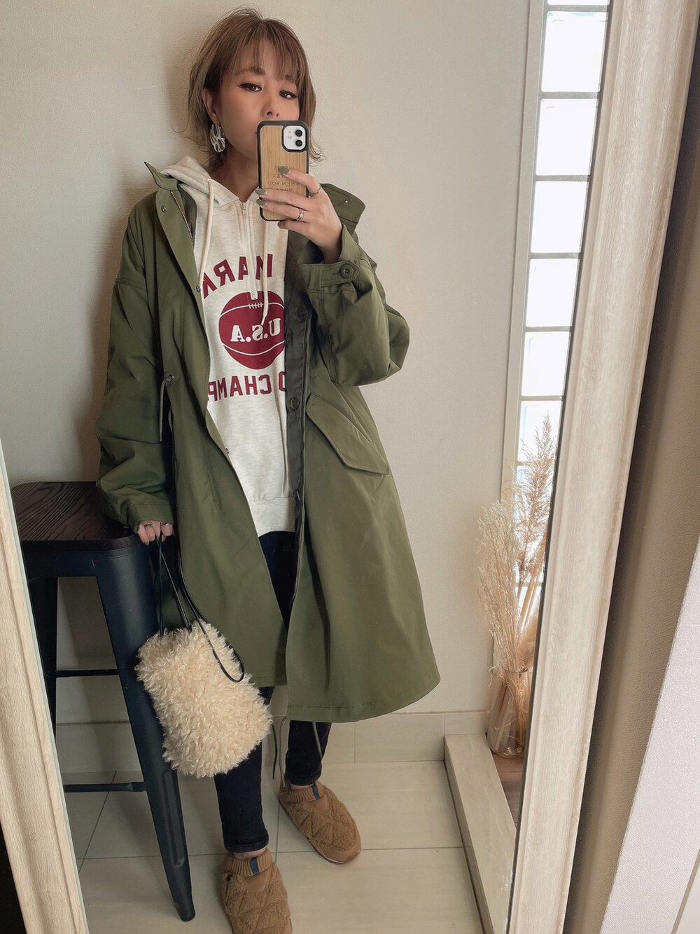 グリーン系のモッズコート、ホワイト系のショルダーバッグ、ベージュ系のスリッポンを着用したレディースの秋コーディネートの2枚目の写真