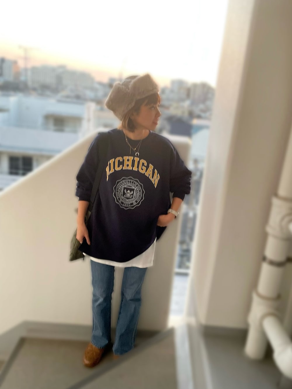 ブラウン系のスニーカー、グリーン系のショルダーバッグ、ブルー系のデニムパンツを着用したレディースの冬コーディネートの3枚目の写真