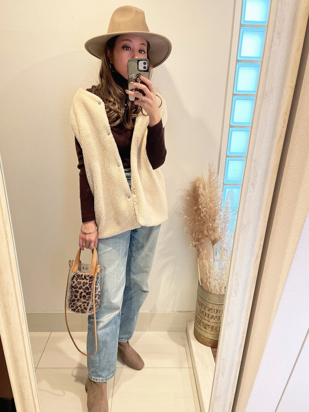 ホワイト系のベスト、ブルー系のデニムパンツ、ベージュ系のショルダーバッグを着用したレディースの秋コーディネートの4枚目の写真