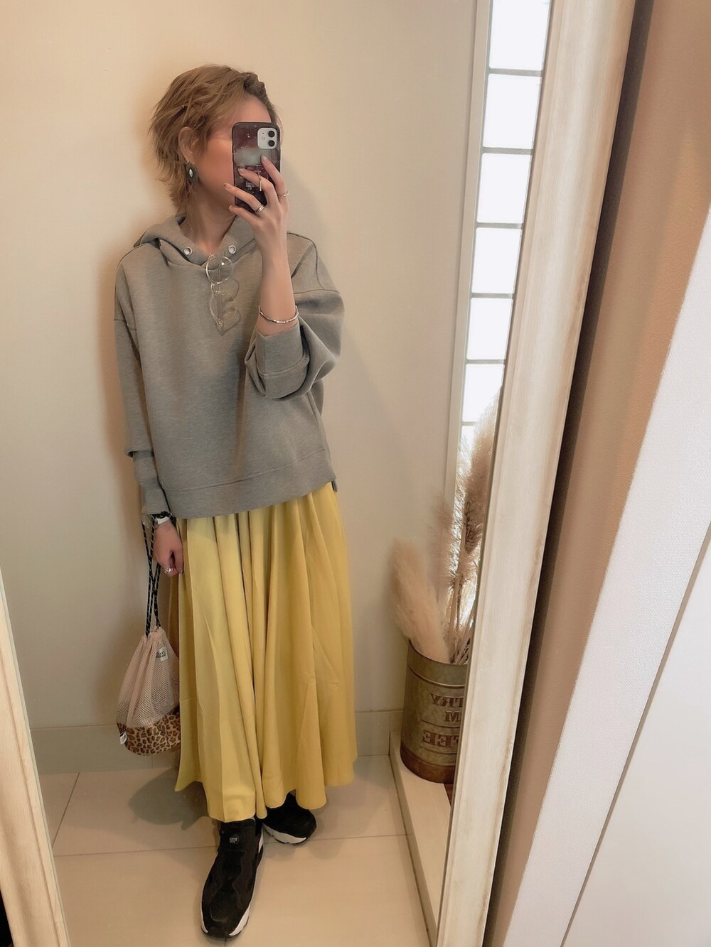 イエロー系のスカート、ブラック系のスニーカー、グレー系のパーカーを着用したレディースの春コーディネートの3枚目の写真