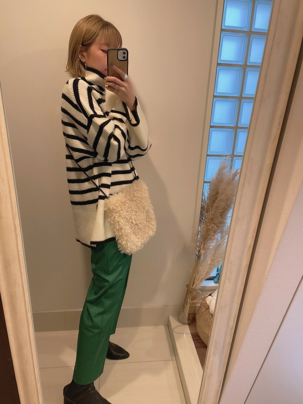 ホワイト系のニット/セーター、グリーン系のスラックス、ブラック系のブーツを着用したレディースの冬コーディネートの2枚目の写真