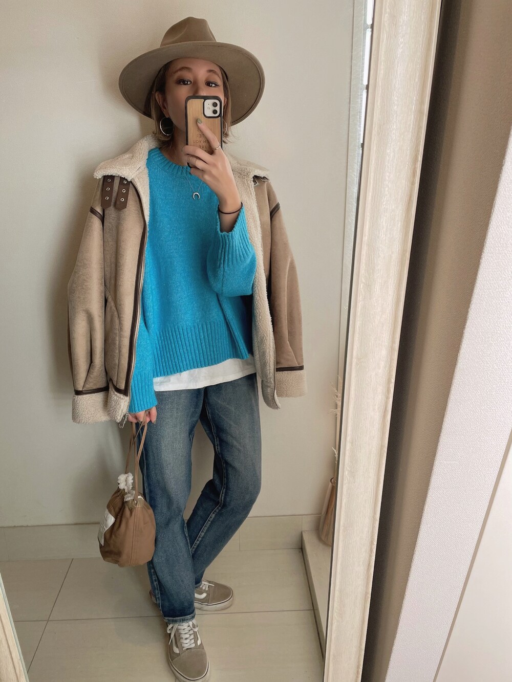 ブルー系のニット/セーター、ベージュ系のブルゾン、ブラウン系のクラッチバッグを着用したレディースの冬コーディネートの4枚目の写真