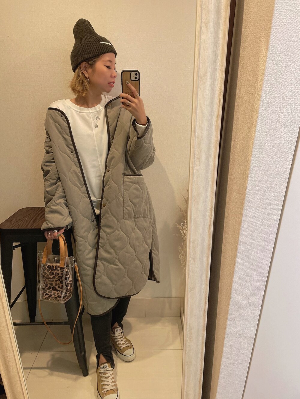 グリーン系のノーカラーコート、ベージュ系のショルダーバッグ、ブラック系のデニムパンツを着用したレディースの秋コーディネートの2枚目の写真