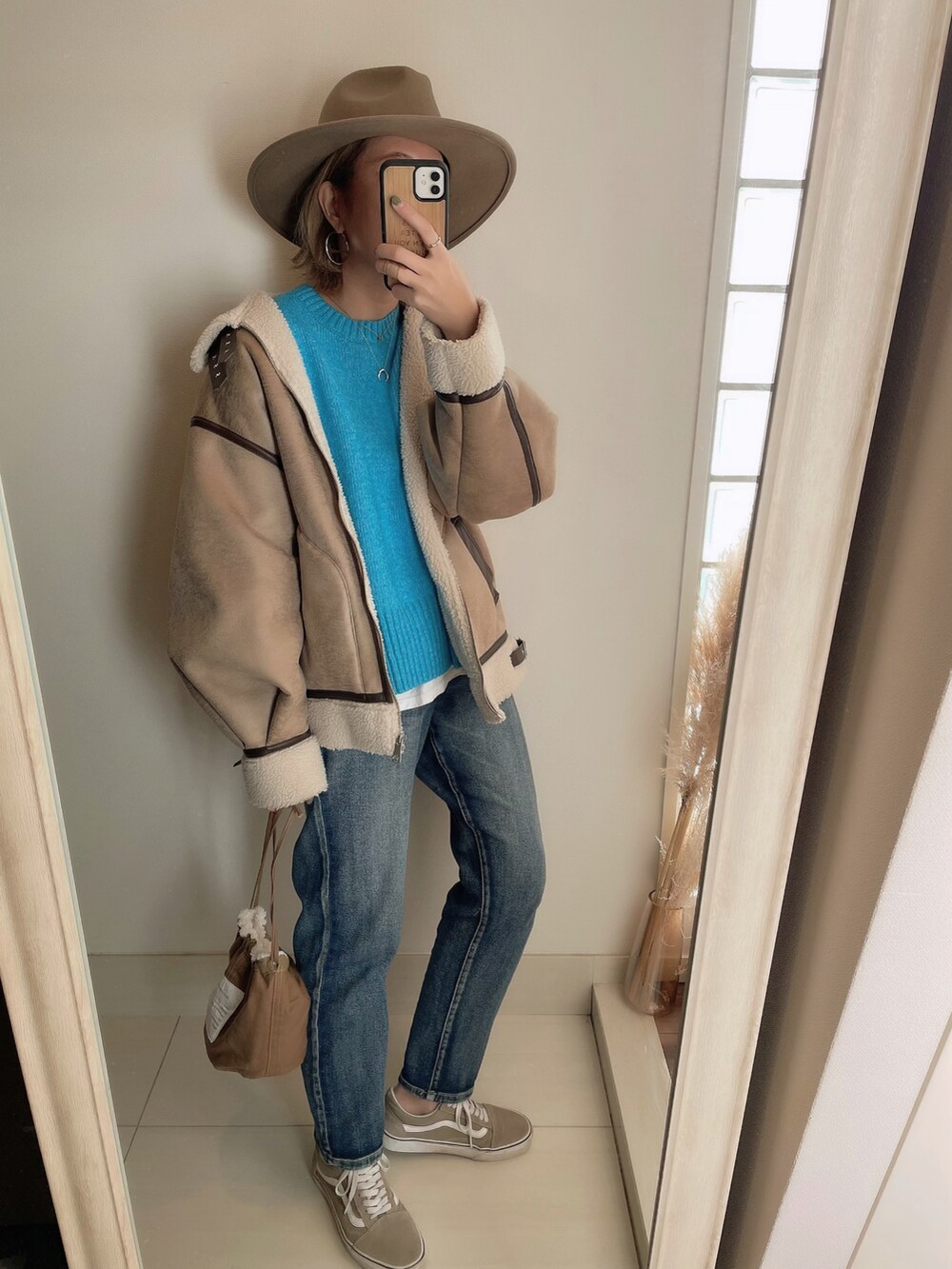 ブルー系のニット/セーター、ベージュ系のブルゾン、ブラウン系のクラッチバッグを着用したレディースの冬コーディネートの2枚目の写真