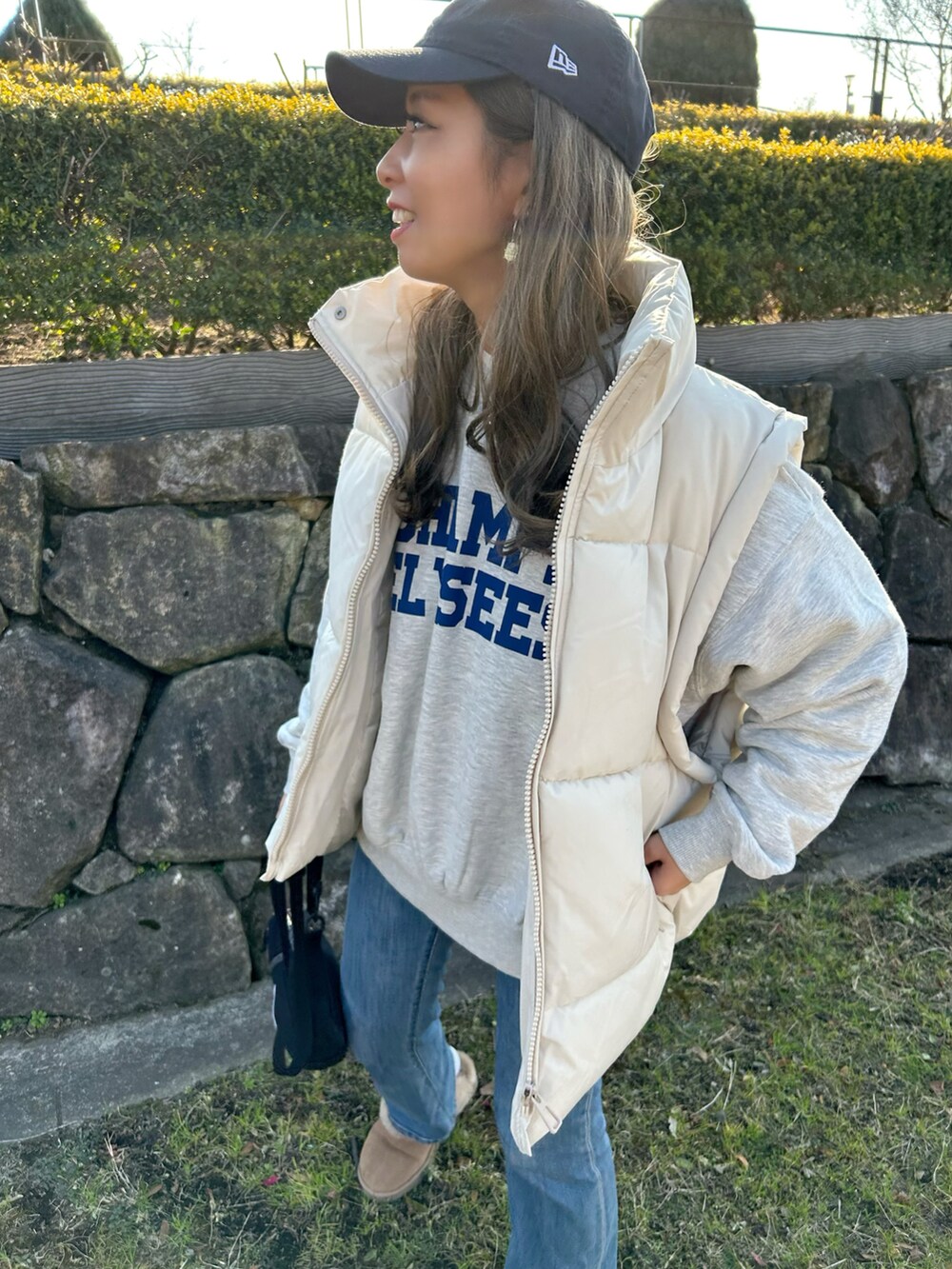 ベージュ系のダウンベスト、ホワイト系のトップス、ブルー系のデニムパンツを着用したレディースの冬コーディネートの4枚目の写真