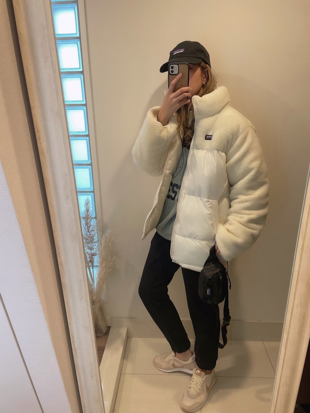 ベージュ系のスニーカー、ブラック系のボディバッグ/ウエストポーチ、ホワイト系のダウンジャケット/コートを着用したレディースの冬コーディネートの2枚目の写真