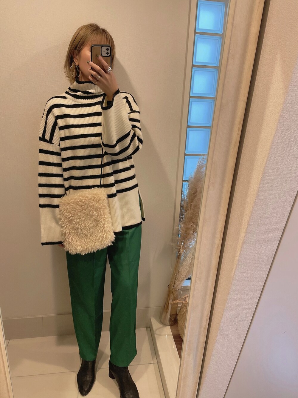 ホワイト系のニット/セーター、グリーン系のスラックス、ブラック系のブーツを着用したレディースの冬コーディネートの3枚目の写真