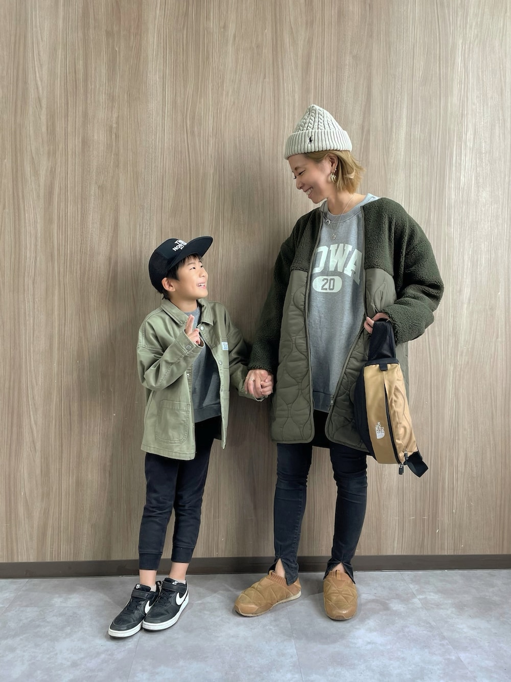 グリーン系のノーカラーコート、ブラウン系のボディバッグ/ウエストポーチ、ブラック系のデニムパンツを着用したレディースの秋コーディネートの4枚目の写真