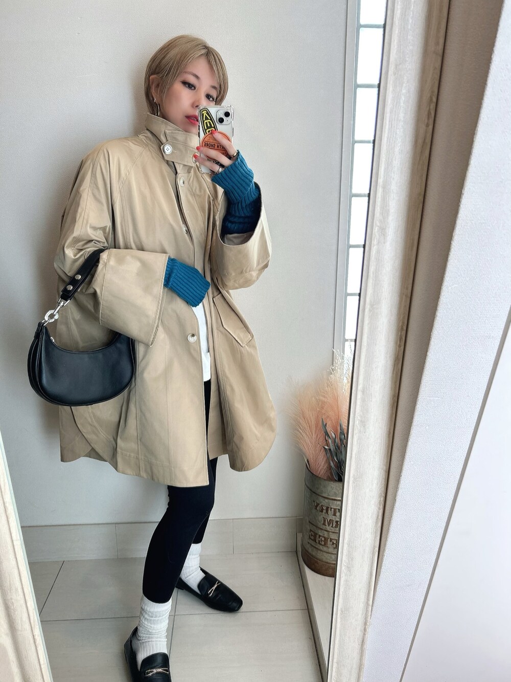 ベージュ系のステンカラーコートを着用したレディースの春コーディネートの2枚目の写真