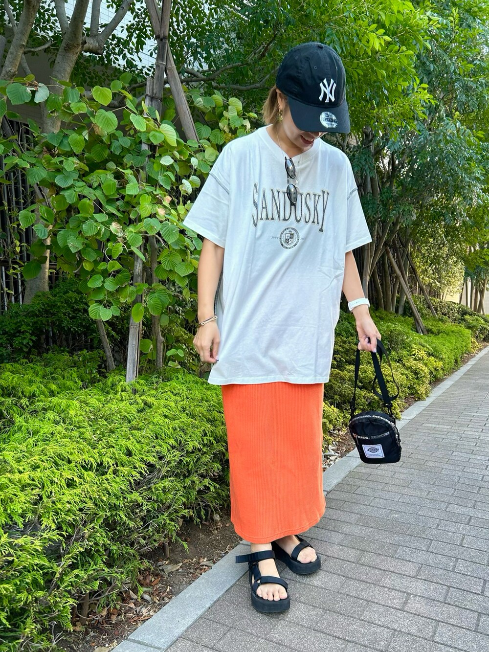 ホワイト系のTシャツ/カットソー、オレンジ系のスカート、ブラック系のサンダルを着用したレディースの夏コーディネートの2枚目の写真