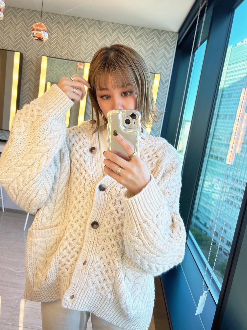 ホワイト系のカーディガン/ボレロ、ベージュ系のハンドバッグ、ブラウン系のスニーカーを着用したレディースの秋コーディネートの3枚目の写真