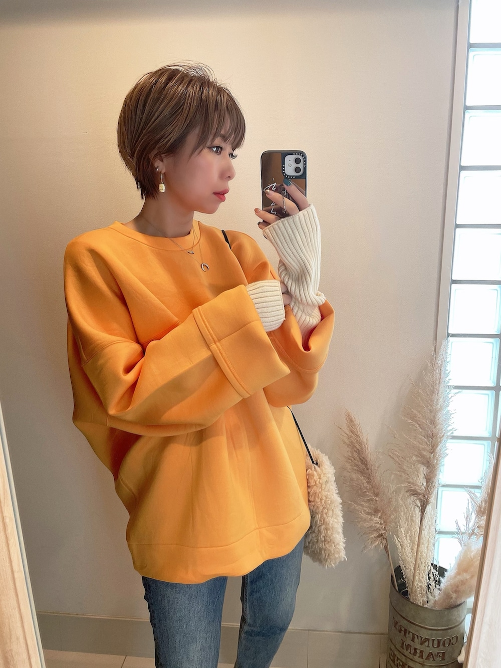 オレンジ系のスウェット、その他のバレエシューズ、ホワイト系のショルダーバッグを着用したレディースの冬コーディネートの4枚目の写真