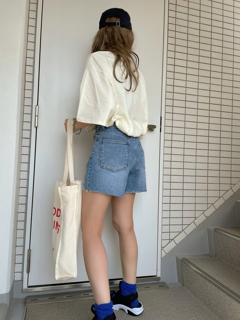 ブラック系のサンダル、ブルー系のキャップを着用したレディースの夏コーディネートの3枚目の写真