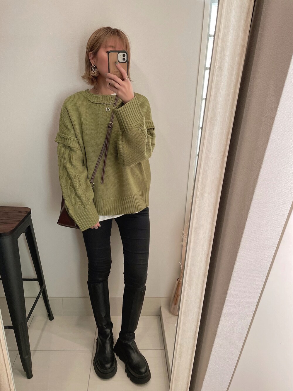 グリーン系のニット/セーター、ブラック系のブーツ、ブラック系のデニムパンツを着用したレディースの冬コーディネートの2枚目の写真